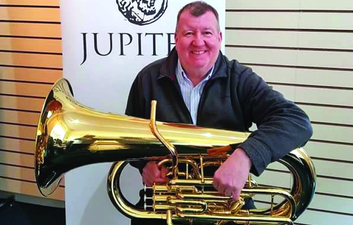 Ronnie is holding a shiny bass in front of a Jupiter sign