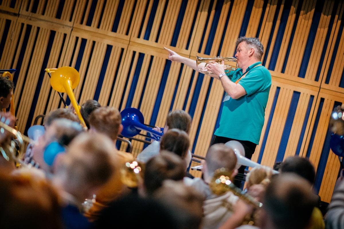 tutor playing a cornet with a group of children learning to play instruments