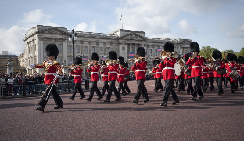Band of guards marching whilst playing instruments, wearing red uniforms