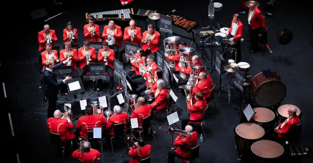 A photo of Cory Band sat in a semicircle performance formation