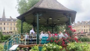A photo of a band stand in a garden with a brass band playing