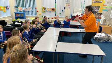 Children playing brass instruments in a classroom