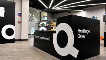 Heritage Quay welcome desk is a large black rectangle with a large Q on the front in white