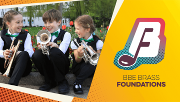 Three children are sitting on the edge of a grassy curb, holding brass instruments