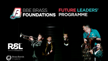 Group of boys and girls playing different brass instruments under very dark lighting - a music tutor wearing a bright green shirt looks over