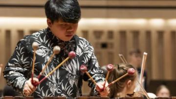 Boy playing a xylophone, holding three mallets in each hand