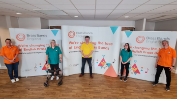 Five people spaced out all wearing different brightly coloured polo tops with jeans