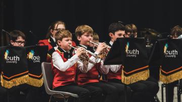 Children playing cornets in a brass band, wearing red waistcoats