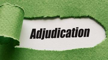 A piece of green paper has been ripped and pulled out to reveal the word Adjudication written in black on white