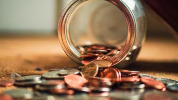 Money spilling out of a glass jar