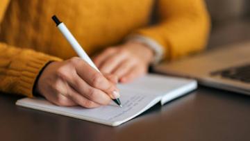 Woman writing in a notepad on a desk