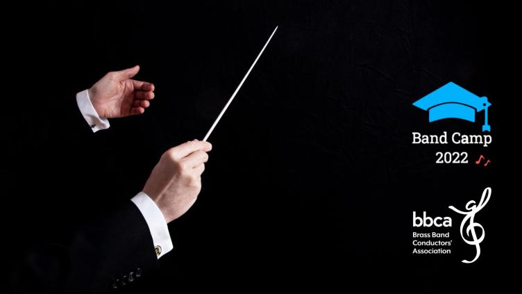A male conductor's hands holding a baton, he is wearing a black jacket and a white shirt