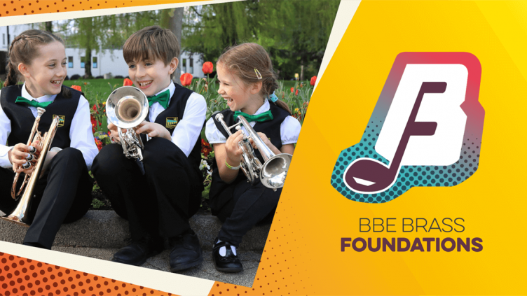 Three children are sitting on the edge of a grassy curb, holding brass instruments