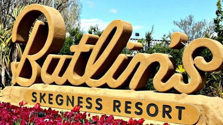 Butlin's sign with giant cut-out letters sits behind a bed of poppies, sign also reads "Skegness Resort"