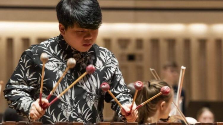 Boy playing a xylophone, holding three mallets in each hand