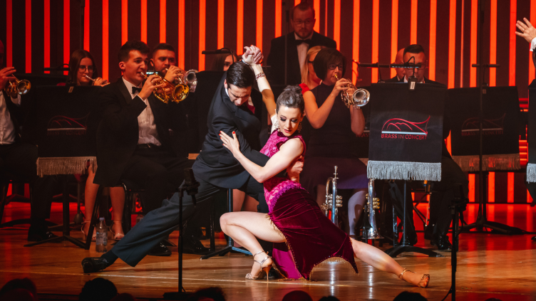 The guest dancers from Brighouse and Rastrick's performance at Brass in Concert 2022 are centre: the man wears a suit while the woman wears a purple velvet dress with side splits at the thigh