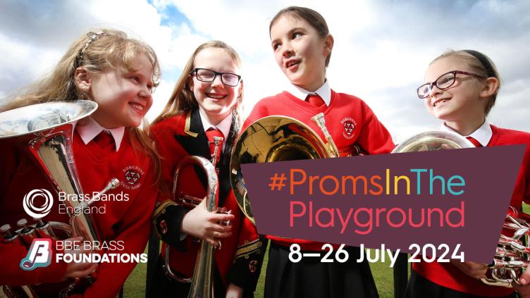 Group of four primary-school aged girls wearing red sweatshirts stood looking at each other in field holding brass instruments and smiling