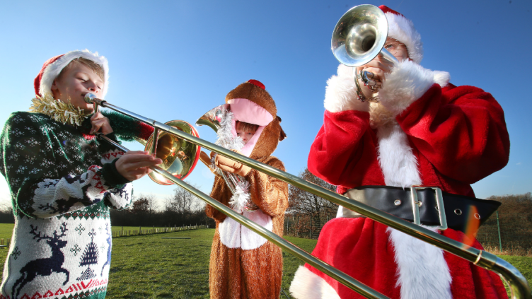 Children playing brass intruments in Christmas costumes