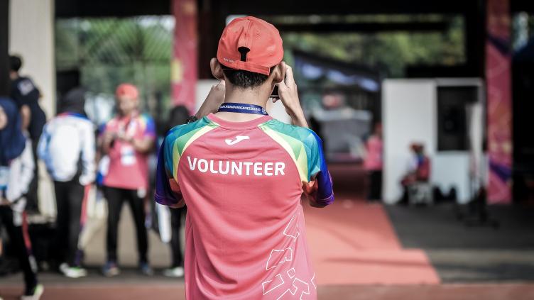 Person facing away from the camera, with a shirt with Volunteer printed on the back