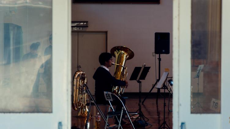 Man playing a brass instrument seen through an open door