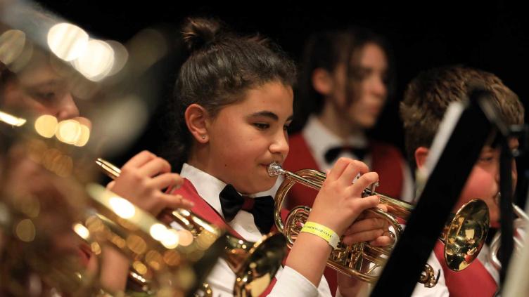 Child in a red waistcoat playing the cornet